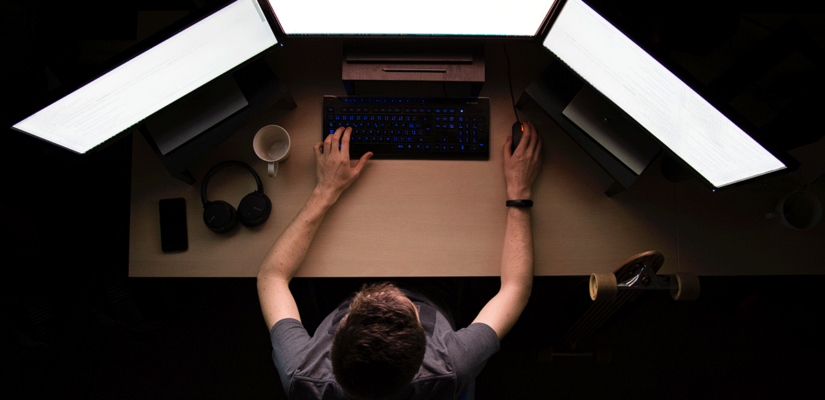 person working at a computer with three screens